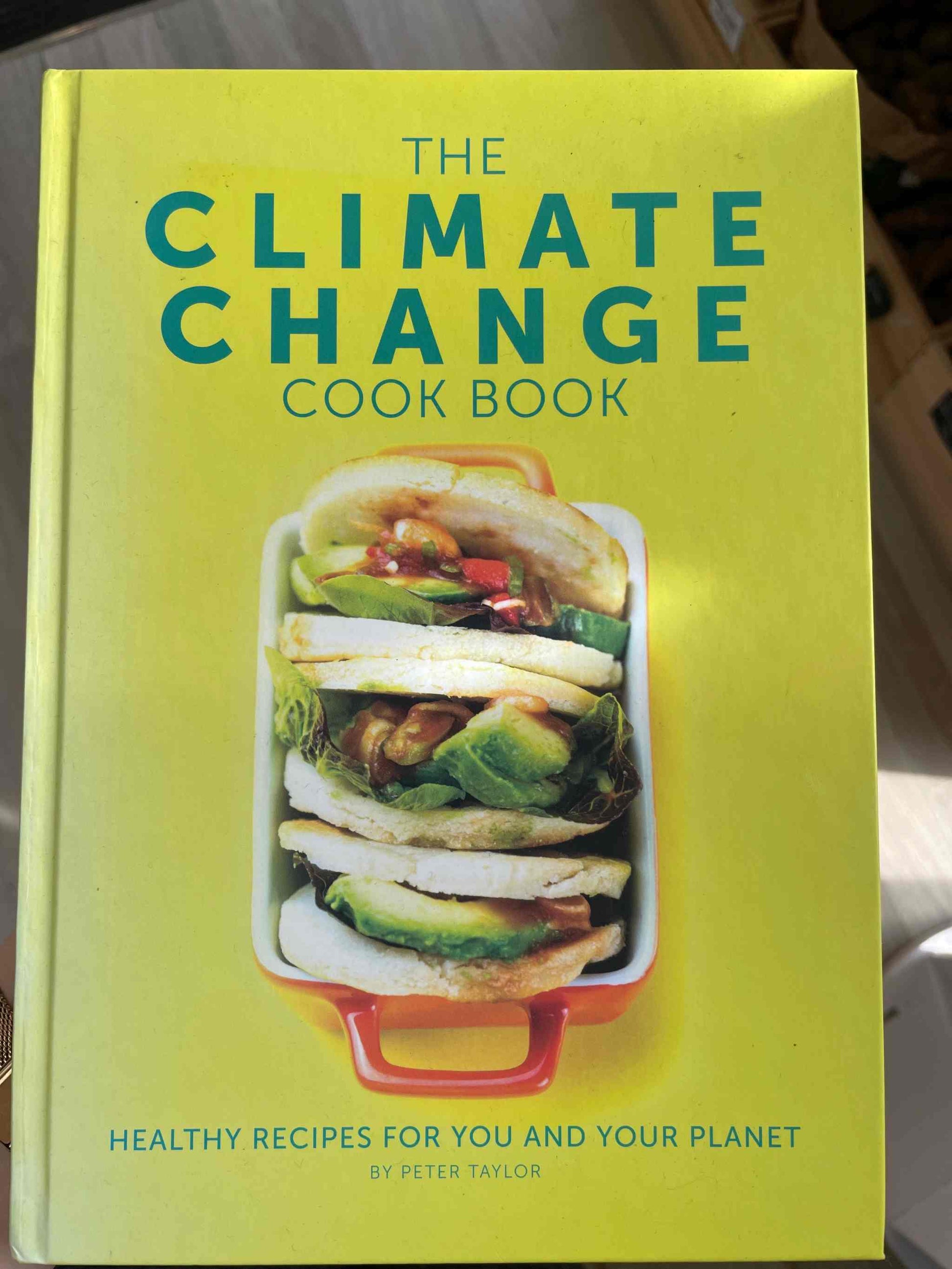 The Climate Change Cook Book cover featuring layered vegetables in a dish, promoting sustainable cooking.