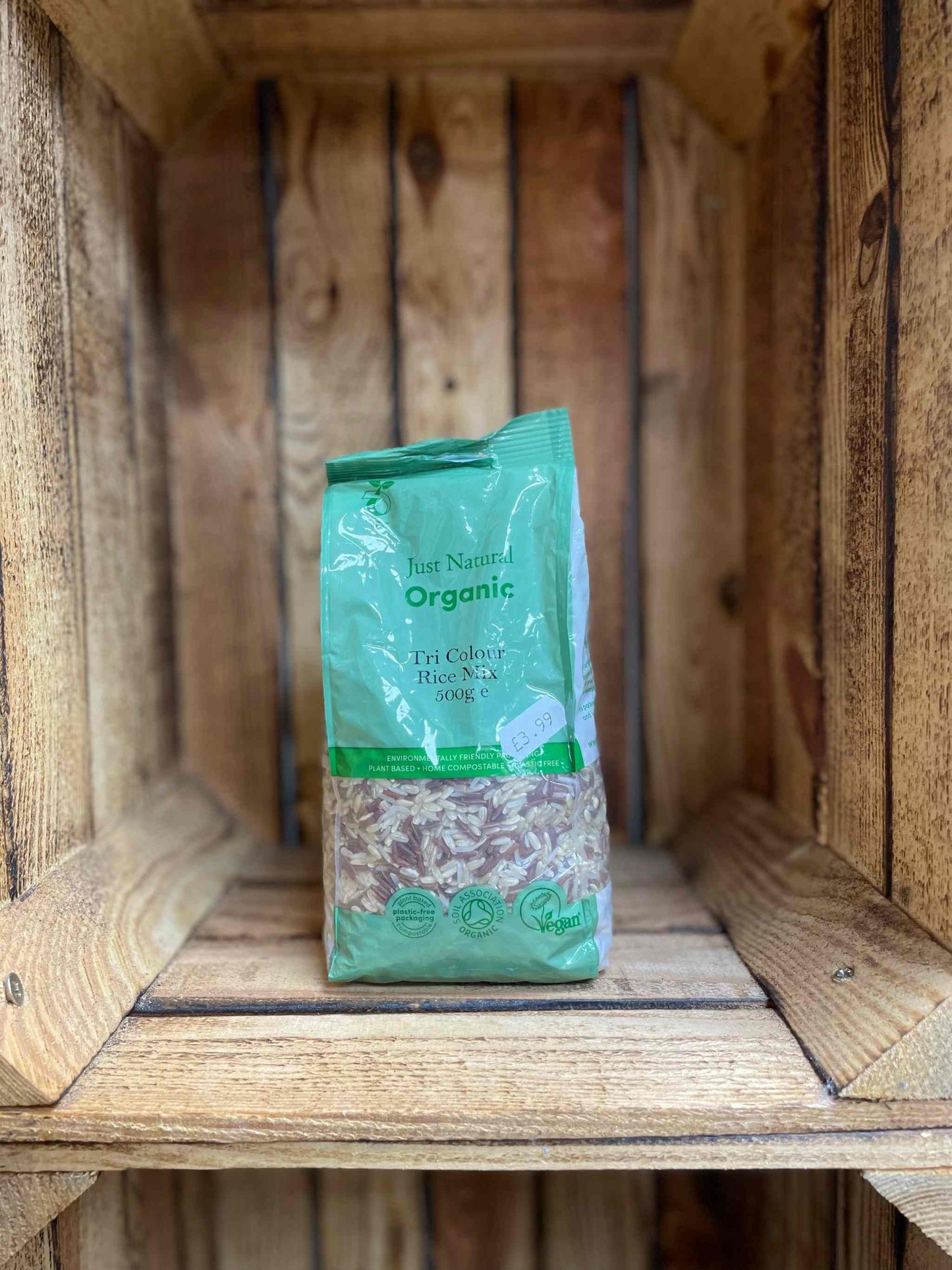 Org Tri Colour Rice Mix 500g in green packaging displayed on a wooden shelf.