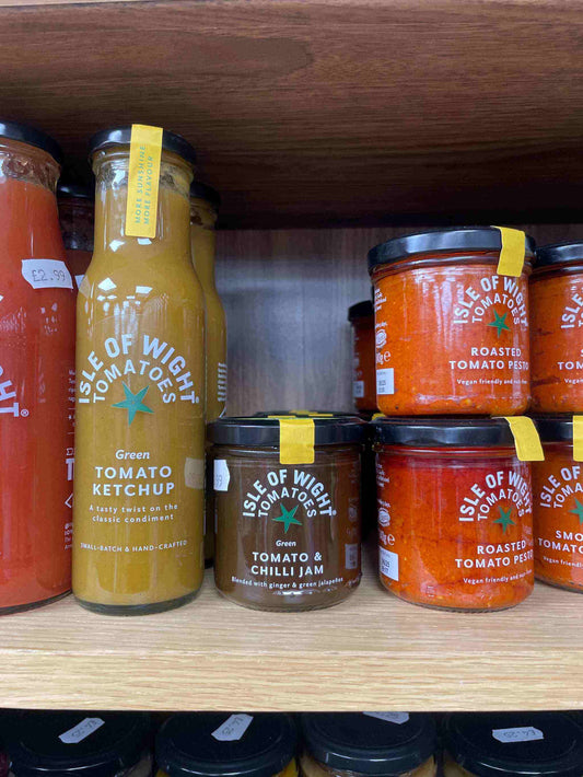 Balsamic vinegar in beautifully designed tomato-stall jars displayed on a shelf.