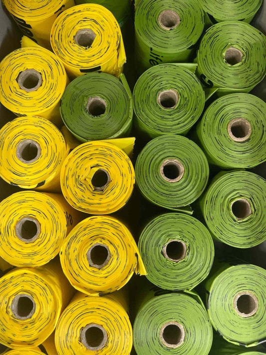 Eco-friendly corn starch poop bags in yellow and green rolls.