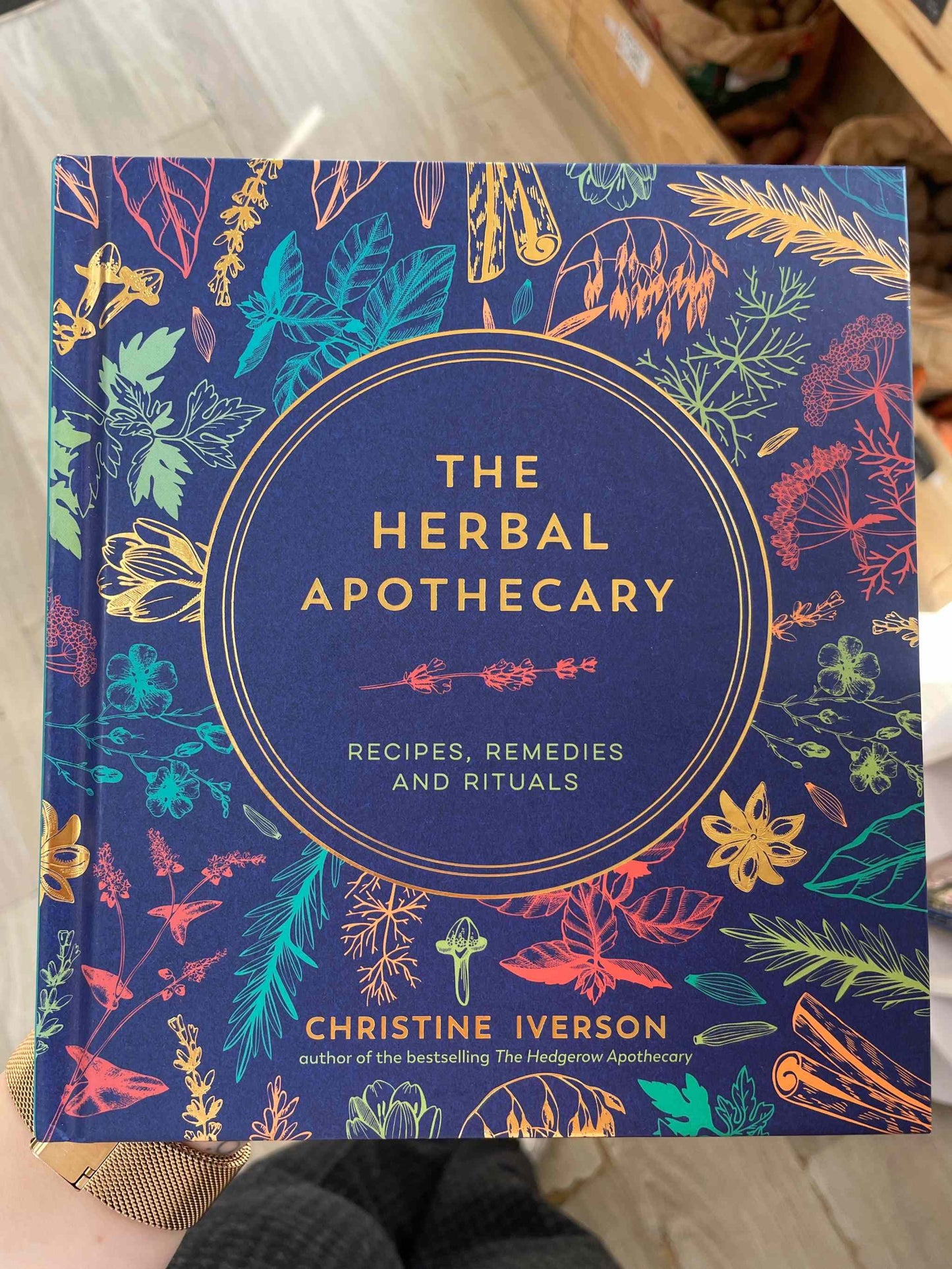 The Herbal Apothecary book cover with vibrant botanical illustrations.