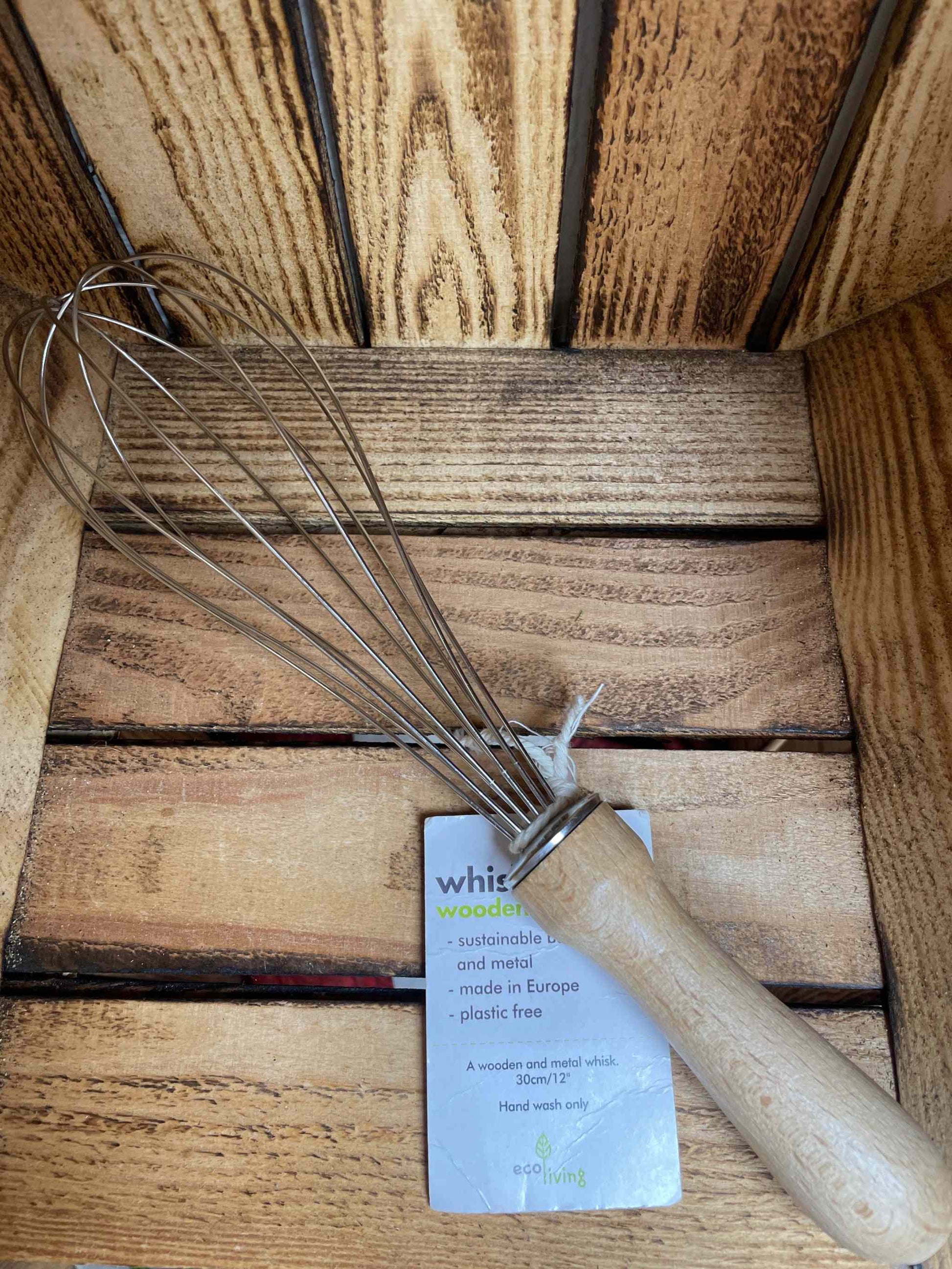 Wooden whisk with FSC sustainable wood handle in rustic setting.