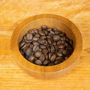 Freshly roasted Colombian decaf coffee beans in a wooden bowl, 100g pack.